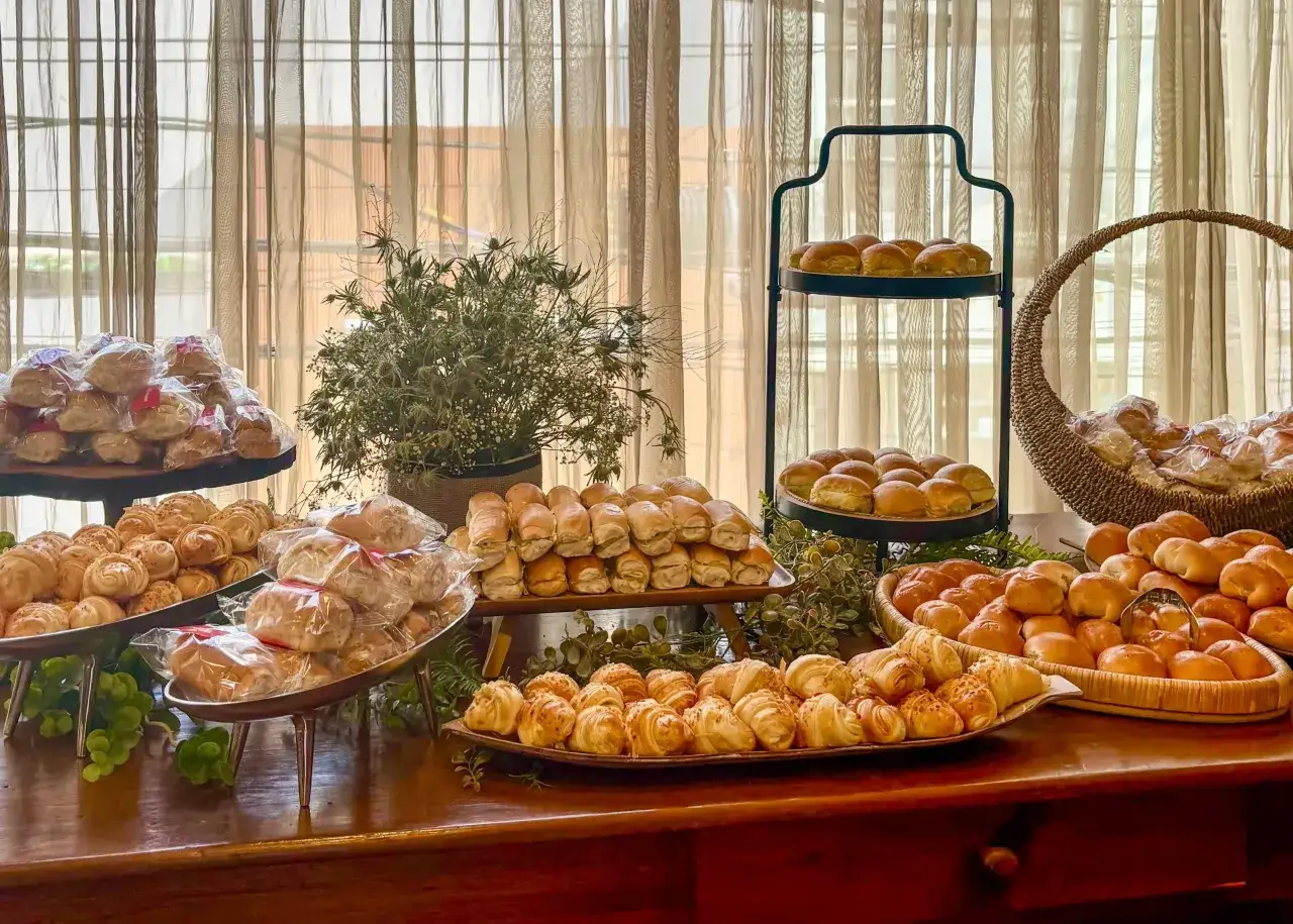 Montaje de coffee break con variedad de panes y bollos, algunos envueltos individualmente, listos para disfrutar.
