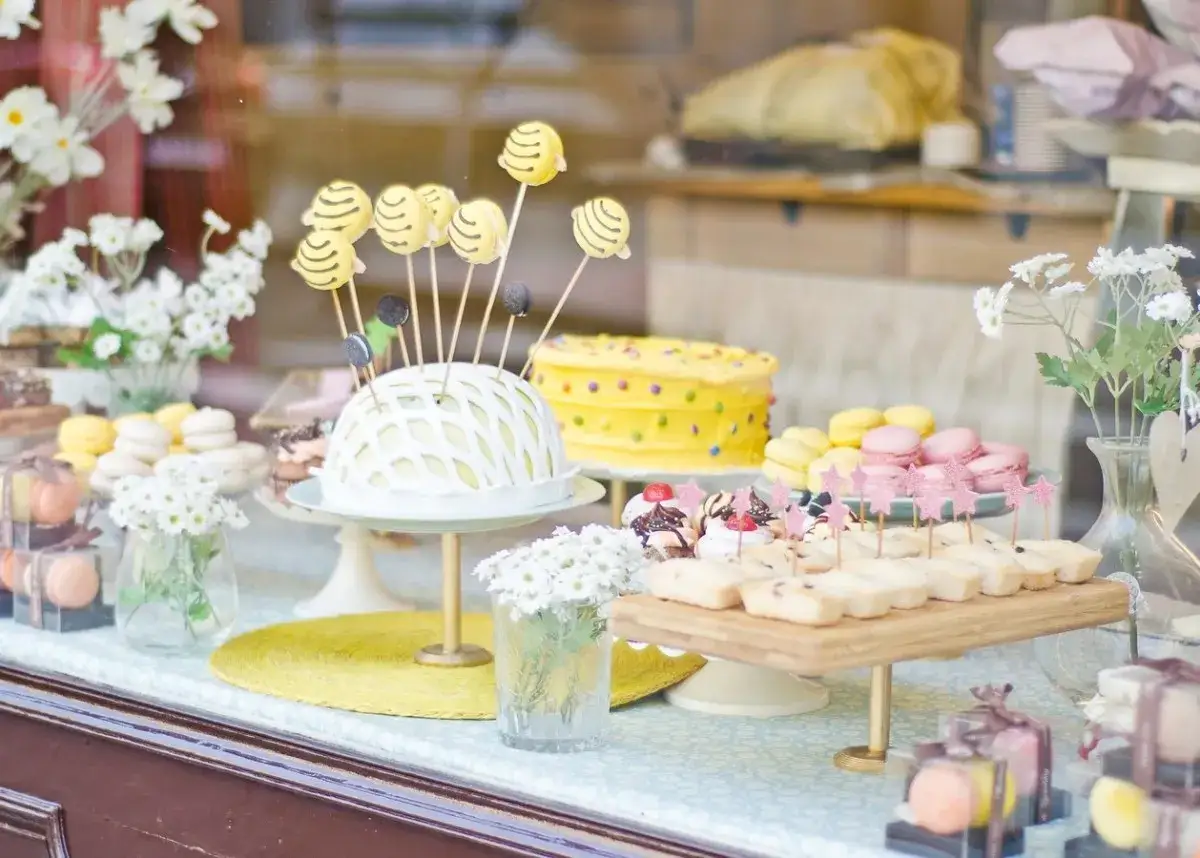Deliciosa comida para revelaci&oacute;n de g&eacute;nero: pastel amarillo con lunares, macarrons rosas y amarillos, y bocaditos dulces.