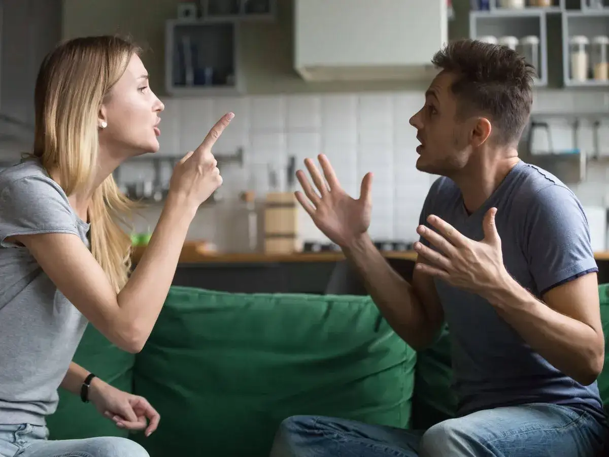 Pareja discutiendo acaloradamente en el sof&aacute;. Ella le se&ntilde;ala con el dedo, &eacute;l gesticula. A veces, hay que luchar por amor.