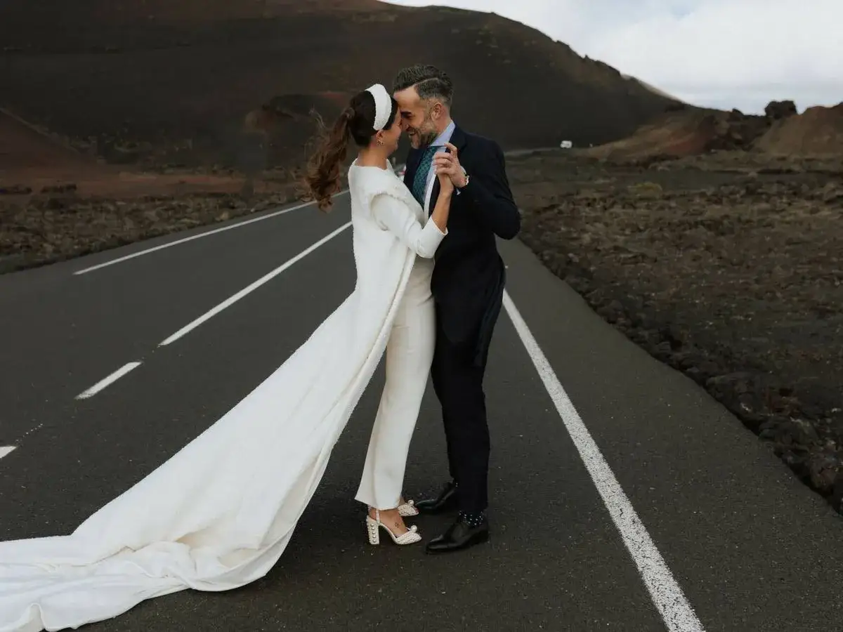Pareja celebra su segunda boda a los 50 a&ntilde;os de edad en una carretera des&eacute;rtica. Ella luce un traje de novia blanco con velo largo, &eacute;l un traje oscuro.