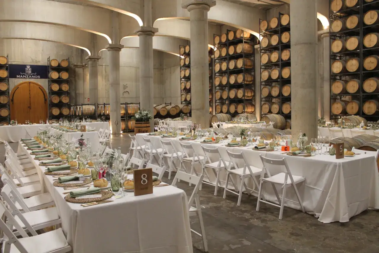 Mesas puestas en una bodega con barricas, perfectas para ideas catering de eventos.