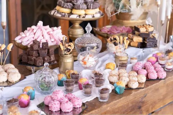 Mesa dulce casera para boda: brownies, malvaviscos rosas, donuts, pastelitos y más.